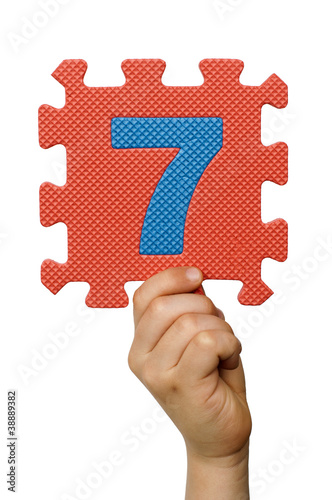 Children hand holding the number Seven. White isolated number