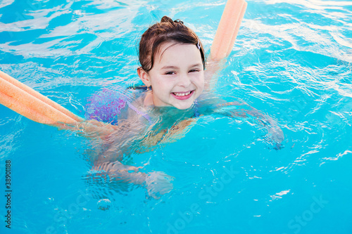 Girl enjoys summer day in swimming pool.