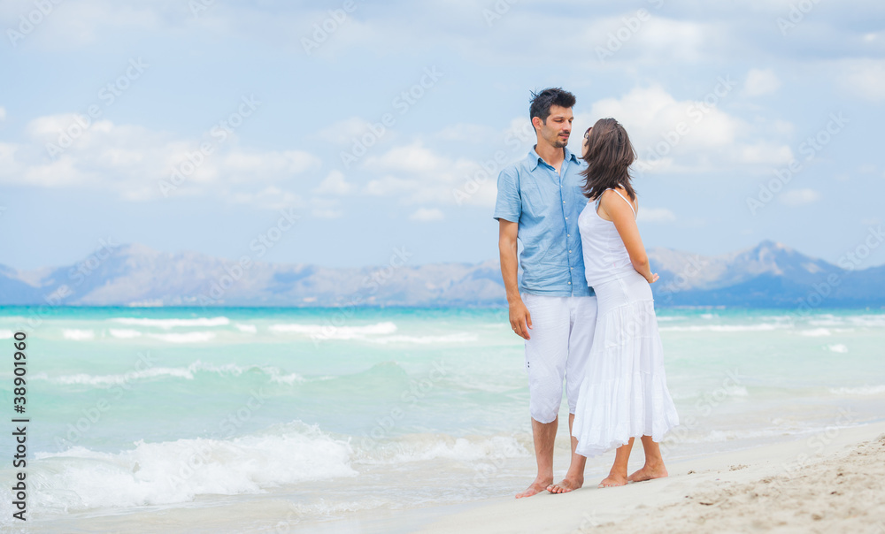 Happy young couple walking on beach