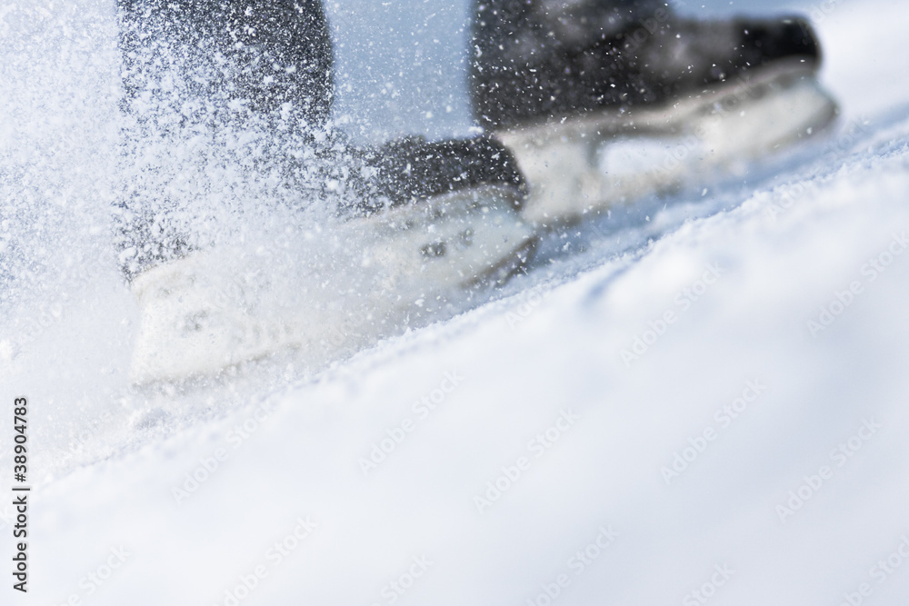 Fototapeta premium Snow flying from braking, ice skates blurred