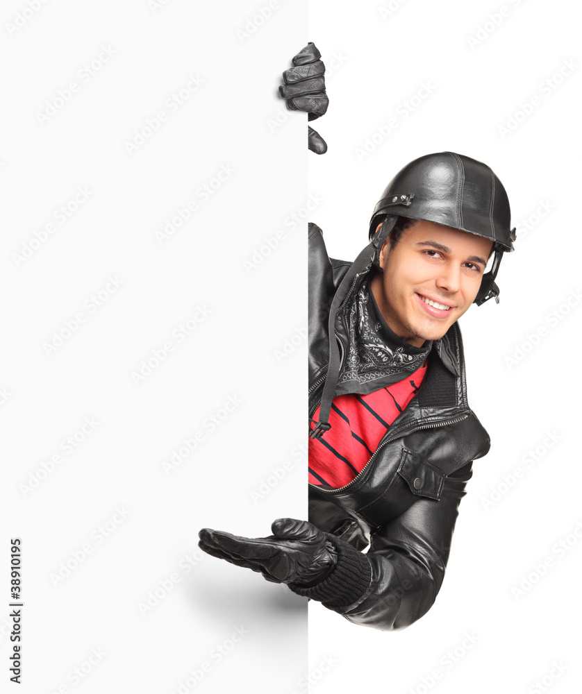 A smiling motorcycler gesturing welcome behind a white panel A smiling motorcycler gesturing welcome behind a white panel