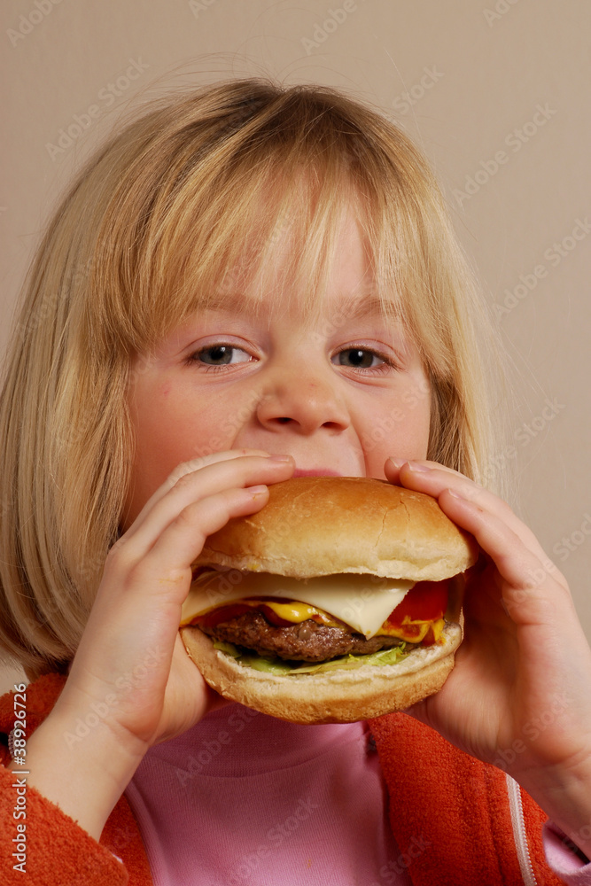 Niña feliz comiendo hamburguesa,comida rápida.