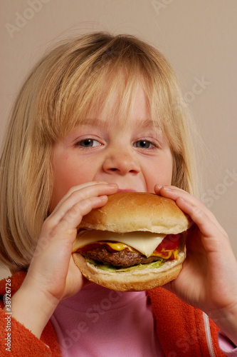 Niña feliz comiendo hamburguesa,comida rápida.