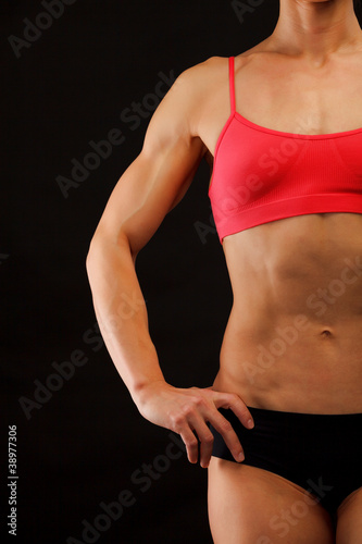 Female fitness bodybuilder posing against black background © Nobilior