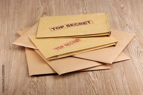 Envelopes with top secret stamp on wooden background photo