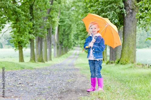 little girl with umbrella in spring alley