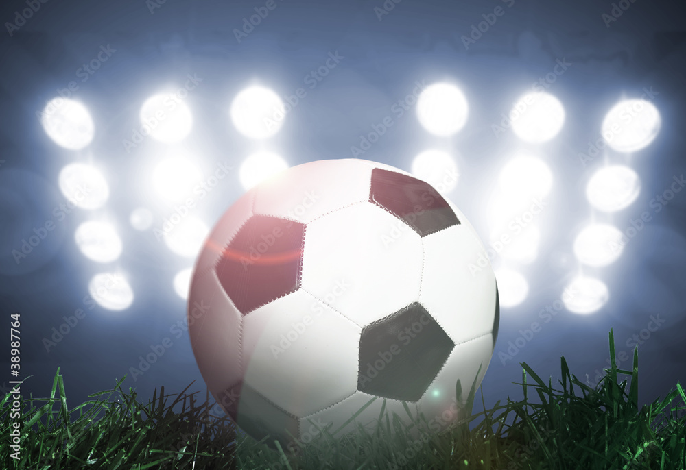 Naklejka premium Soccer ball on grass field with spotlights