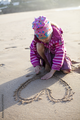 Girl drawing a heart in sand