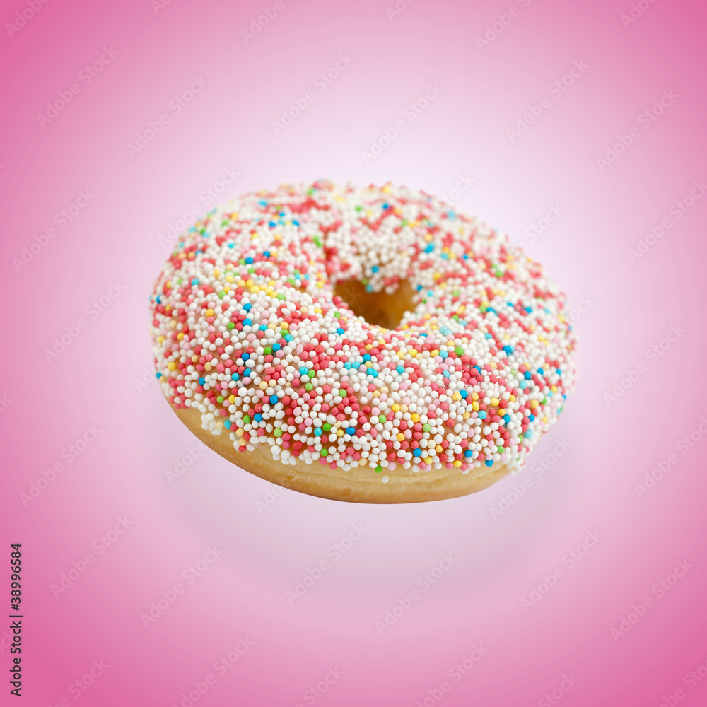 Donut mit bunten Zuckerperlen vor rosa Hintergrund Donut mit bunten Zuckerperlen vor rosa Hintergrund