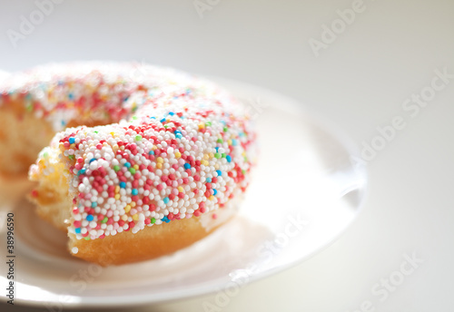 Angebissener Donut mit bunten Zuckerperlen auf einem Teller
