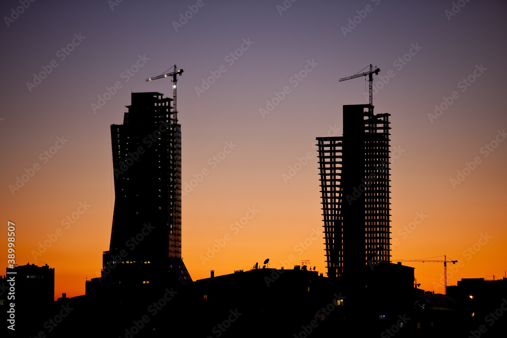 City silhouette during sunset with construction sites and cranes