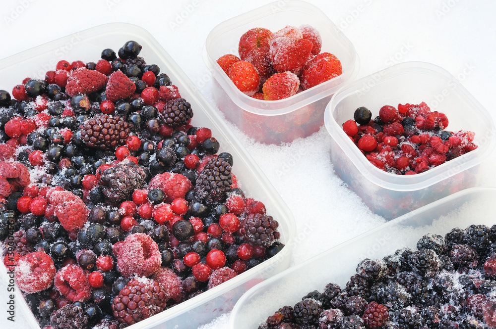 Plastic containers of frozen mixed berries in snow Plastic containers of frozen mixed berries in snow