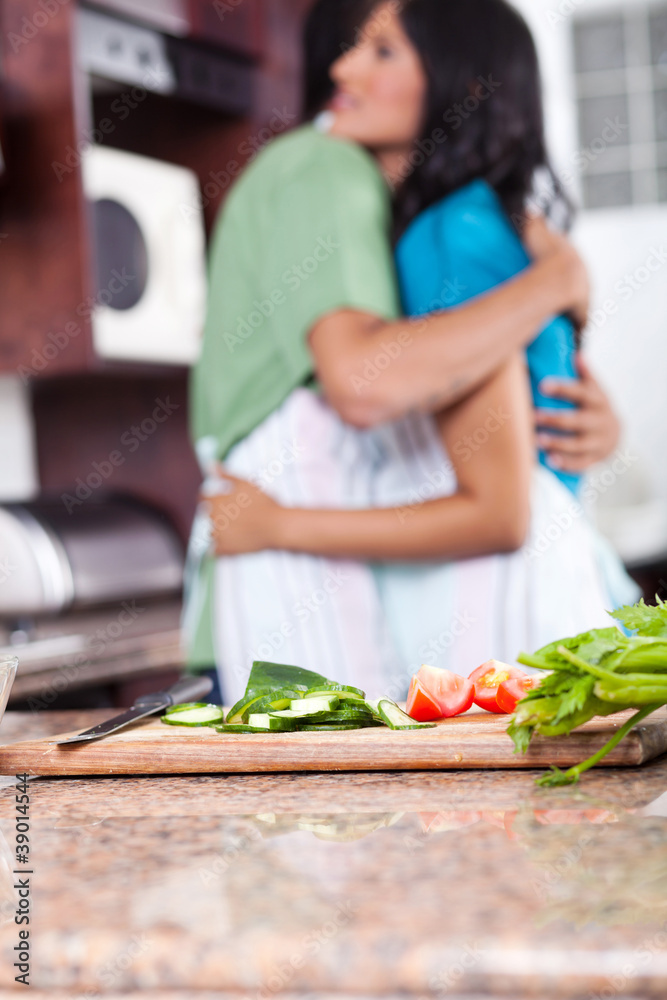 young couple hugging in kitchen, focus on foreground