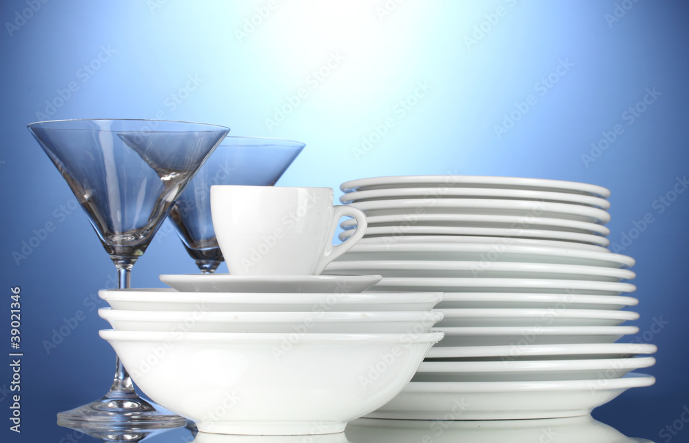 empty bowls, plates, cups and glasses on blue background empty bowls, plates, cups and glasses on blue background