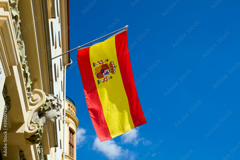 Fototapeta premium Spanish flag waving at an old building