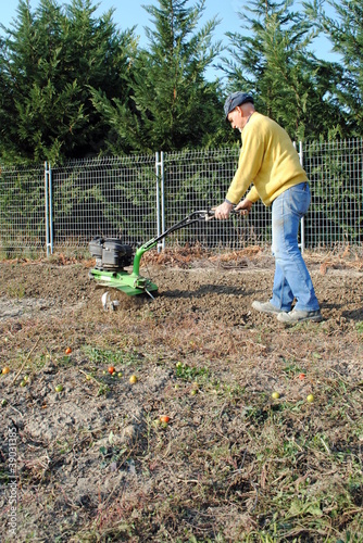 Middle age man with a rototiller in the garden