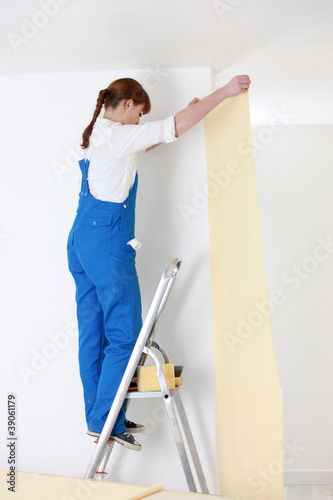 woman on ladder laying wallpaper