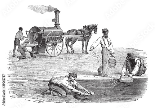 Road workers making pavement with the help of steam engine vinta