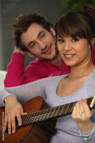 a man looking a woman playing guitar © auremar