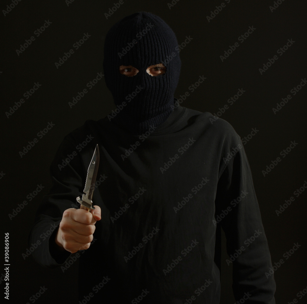 Bandit in black mask with knife isolated on black Bandit in black mask with knife isolated on black