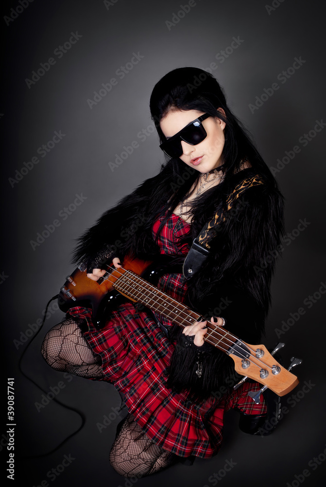 Fashion style photo of young rocked woman in studio  with guitar