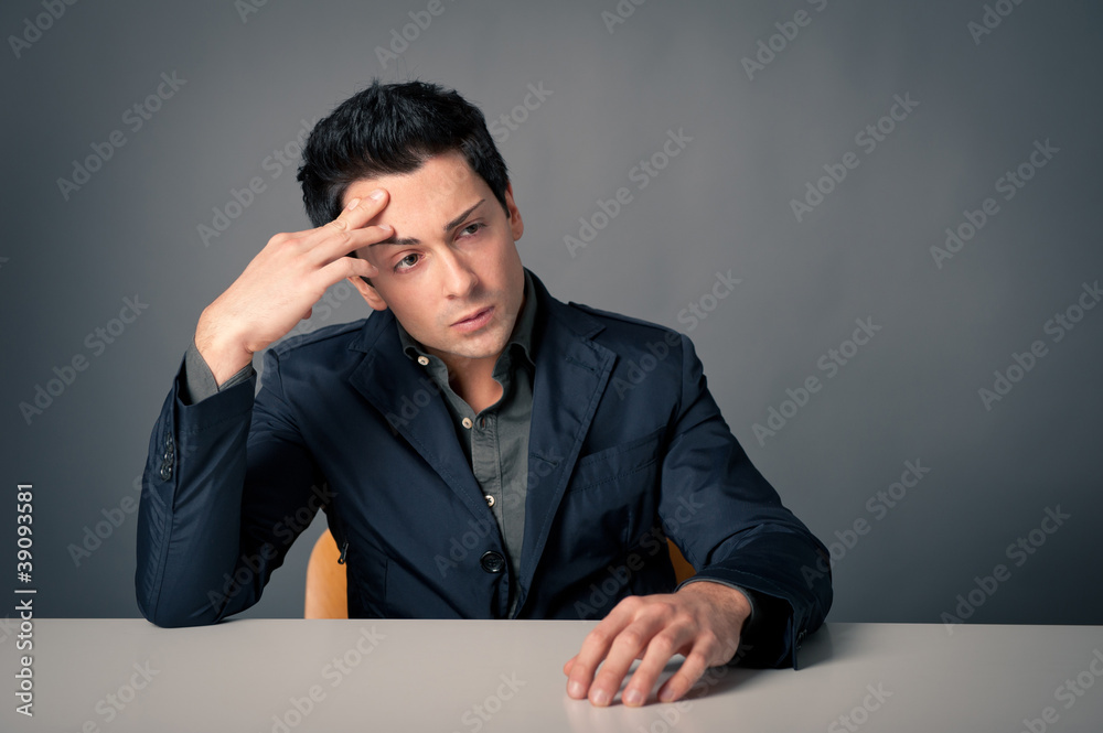 Worried man with desk against dark background. Worried man with desk against dark background.