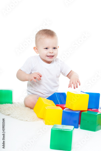 Baby plays with toy blocks over white background