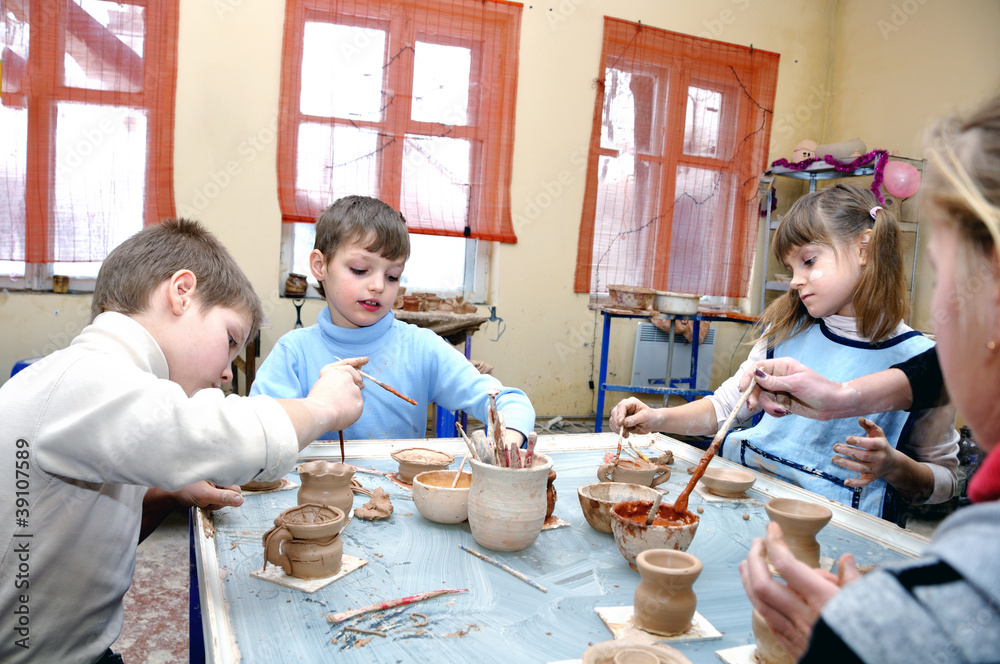 children shaping clay in pottery studio