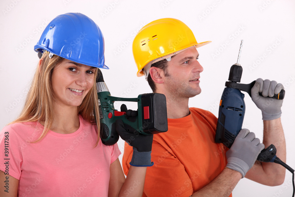 portrait of male and female workers holding electric drill portrait of male and female workers holding electric drill