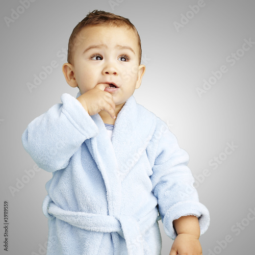 portrait of adorable infant with the finger in his mouth wearing