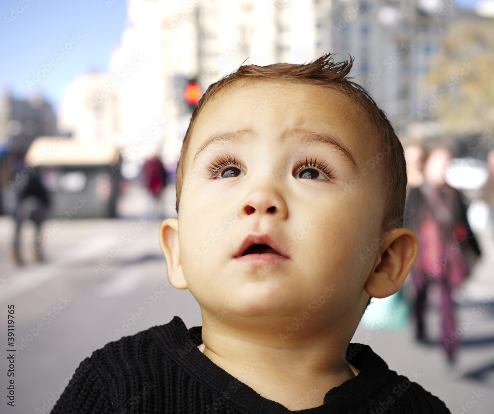 portrait of a handsome kid looking up against at crowded street portrait of a handsome kid looking up against at crowded street