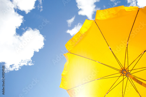 yellow umbrella on blue sky with clouds