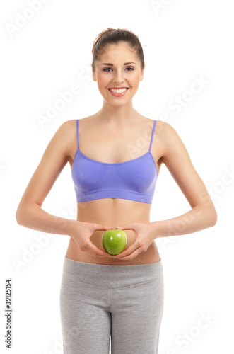 A young and fit brunette woman holding a fresh green apple