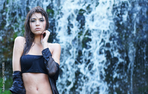 A young brunette model on a waterfall background