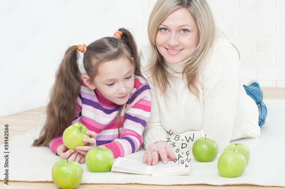 Young mother lying on the floor and reading to her daughter Young mother lying on the floor and reading to her daughter