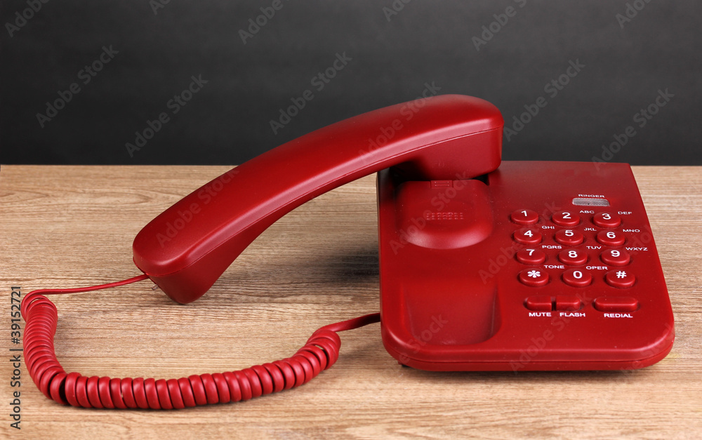 Red phone on wooden table on grey background Red phone on wooden table on grey background