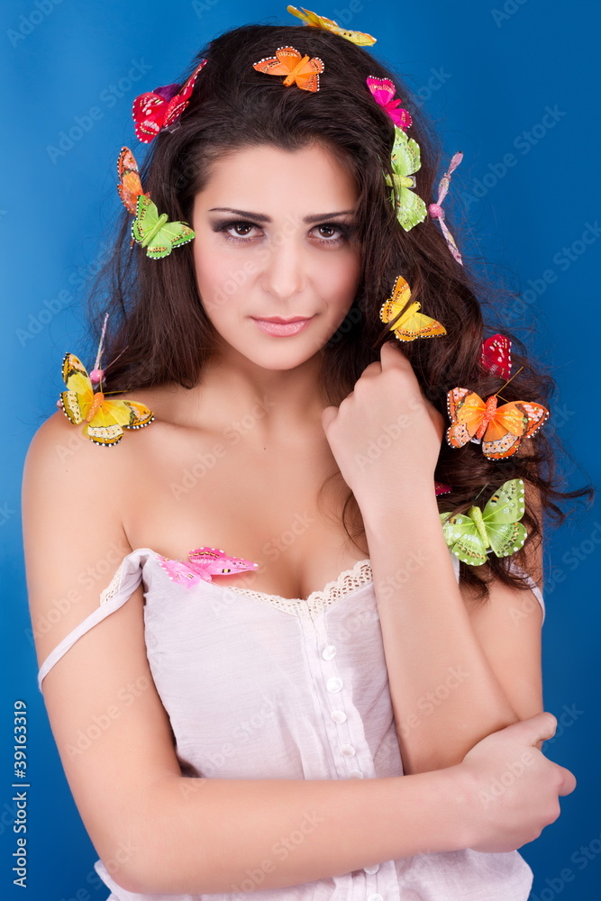 Beautiful girl with butterflies in hair isolated on blue