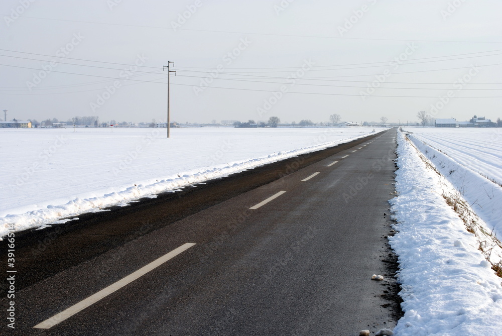 asphalt street in a snow covered farmland landscape