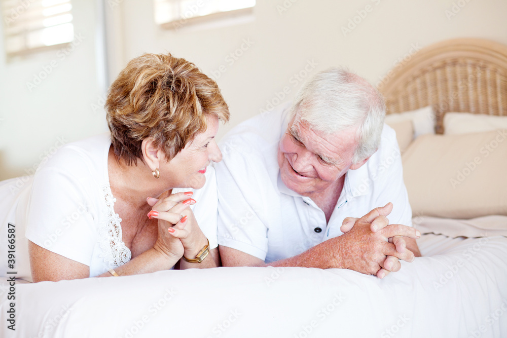 Obraz premium happy senior couple chatting on bed