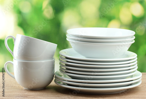 Clean dishes on wooden table on green background