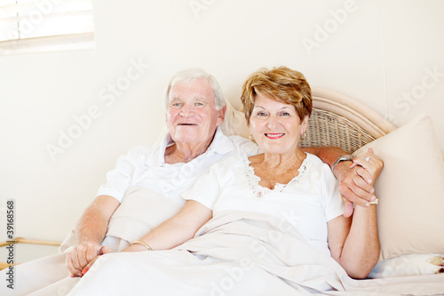 happy senior couple holding hands in bed