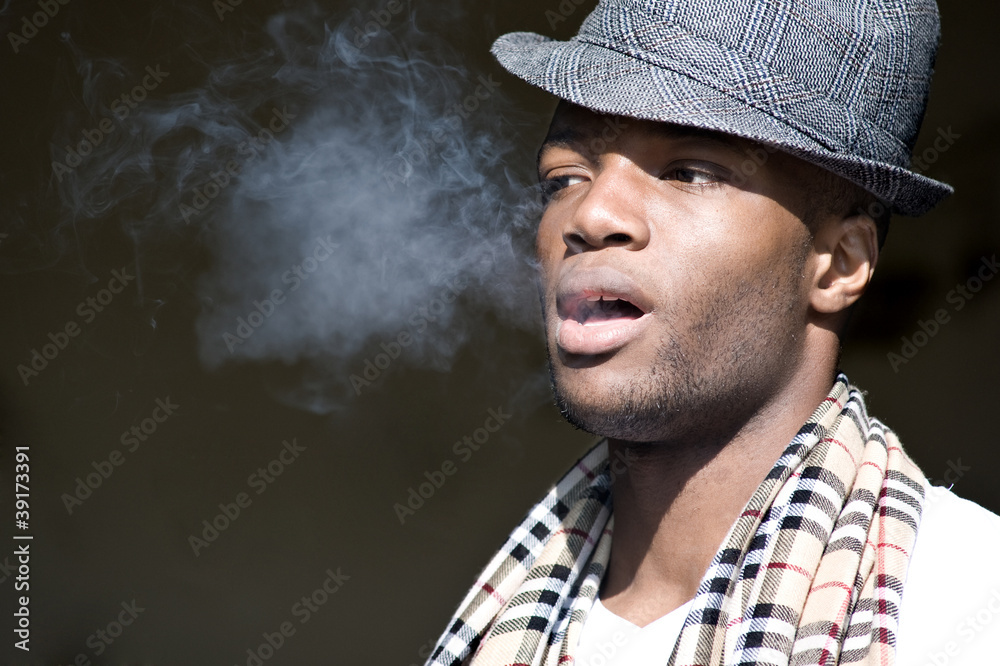 Black man smoking portrait with hat.