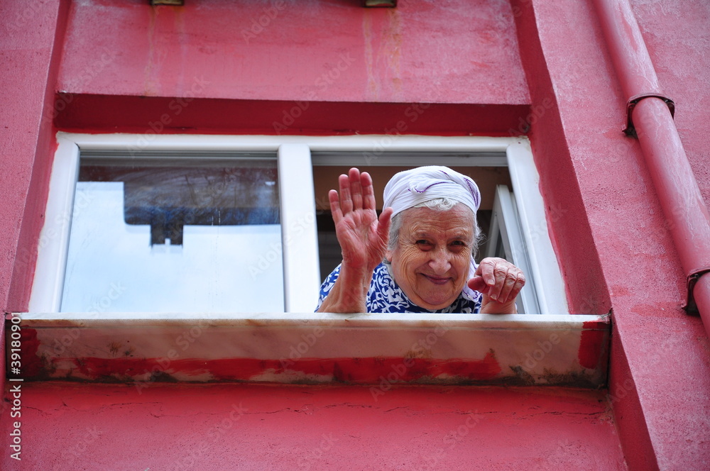 © berna_namoglu - senior woman waving her hand from window