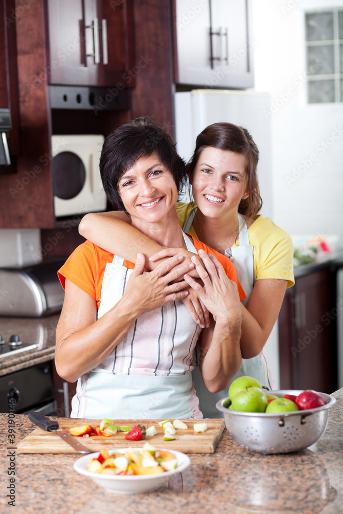 happy mother and teen daughter in kitchen