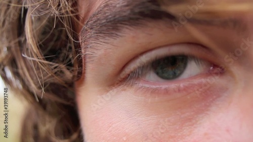 Grey eye of a young man looking sad, blinking
