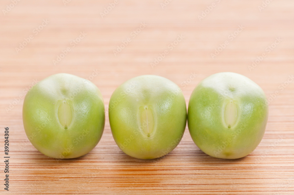 Three fresh green peas on wooden background Three fresh green peas on wooden background