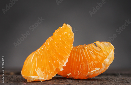 two ripe tangerine cloves on wooden table on grey background