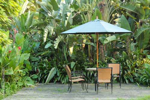 Garden furniture - rattan chairs and table under umbrella on a w