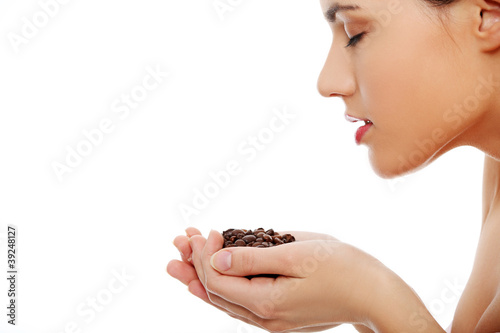 Young woman holding and smelling coffee beans photo