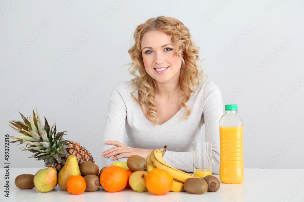 Smiling blond woman sitting with fruits on table Smiling blond woman sitting with fruits on table